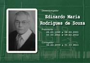Foto de busto preta e branca do Desembargador Edinardo Maria Rodrigues de Souza toga e gravata e...